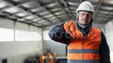 戴着安全帽、穿着工作服的胡子和胡子正站在机库中间，对着镜头竖起大拇指